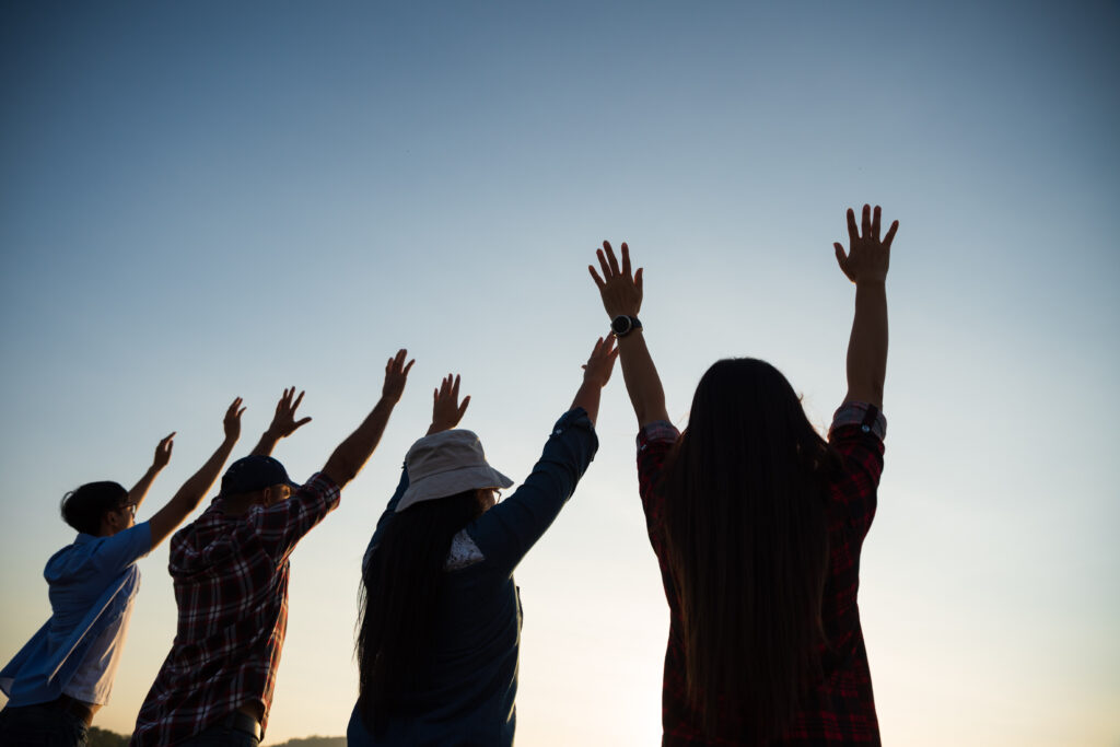 group happy friends are having fun with raised arms together